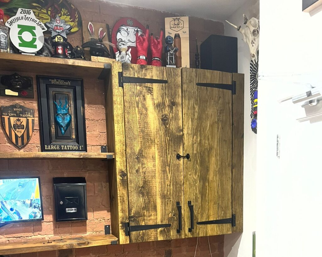 Rustic wooden cupboard with black iron hardware on brickwork