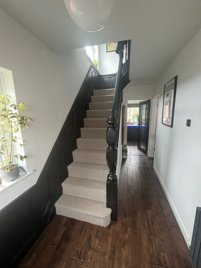 Black painted staircase with neutral carpet and wood flooring