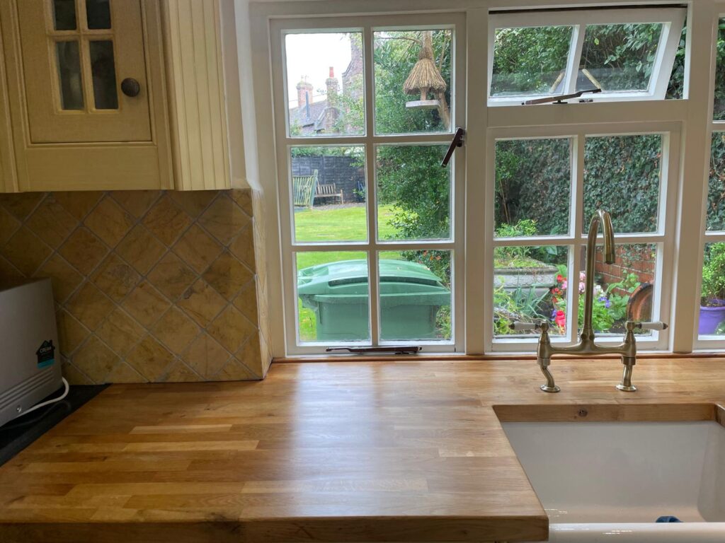 Cream kitchen cabinets with wooden worktop and ceramic sink
