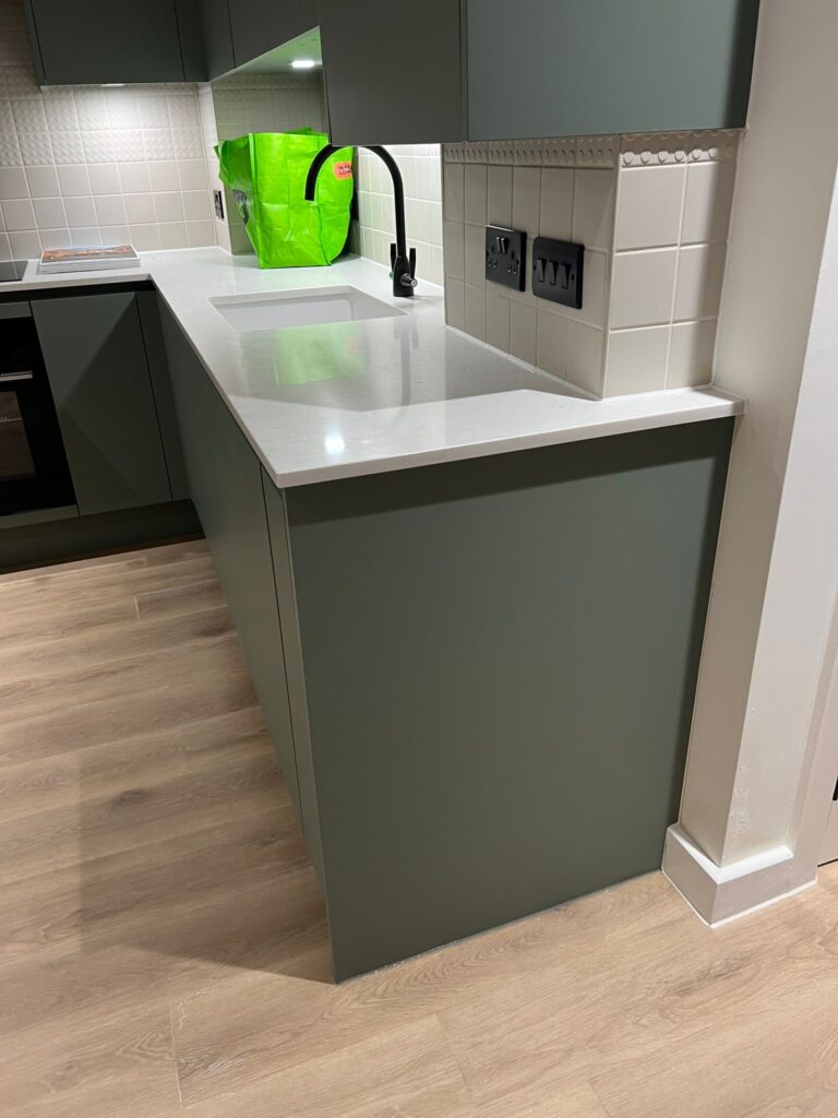 Grey bespoke kitchen cabinetry with white tiled splashback and worktop